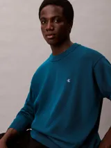 Sweater Calvin Klein de corte relajado, color azul oscuro, con cuello redondo y el logotipo CK bordado en contraste en el pecho. Presenta puños, cuello y dobladillo acanalados.