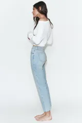 Jeans de tiro alto con diseño cropped flare, confeccionados en denim azul con acabado desgastado. Presentan cinco bolsillos, cierre frontal con cremallera y botón metálico, y bajo con terminación sin costuras.