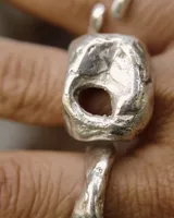 Anillo dorado con forma irregular y un agujero en el centro.