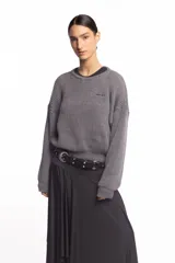 Buzo de punto inglés grueso en color gris melange, de corte amplio con hombros caídos y mangas largas, con sutil bordado de la marca en el pecho.