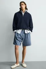 Sudadera regular fit azul marino confeccionada en tejido de algodón con estructura piqué. Cuenta con cuello subido, cierre frontal de cremallera corta y mangas largas con acabados en rib.