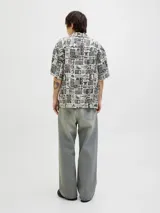 Camisa de manga corta con cuello resort y corte amplio. Presenta un estampado integral en tonos blanco y negro con motivos botánicos y marinos. Confeccionada en tejido liviano de viscosa y lino.