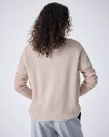 Sweater de punto fino color gris claro, con cuello en V y mangas largas. El tejido parece ser ligeramente transparente o muy liviano.