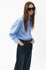 Jean de denim en tono azul oscuro con efecto deslavado, diseño de piernas curvas y corte holgado.