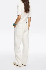 Pantalón vaquero de corte wide leg en color verde claro. Presenta un diseño de tiro medio con cierre frontal de botón y cremallera, además de cinco bolsillos clásicos.