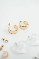 Set de aros variados que incluye aros tipo argolla dorados, aros con piedra brillante, aros tipo argolla de acrílico transparente, aros con diseño de hojas y aros con forma de corazón plateado.