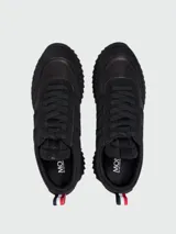 Zapatillas Moncler modelo Pacey de color negro, con diseño de caña baja y suela dentada. Presentan detalles en gamuza y nylon, y una presilla trasera con los colores tricolores de la marca.