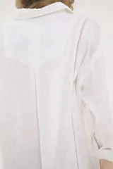 Camisa de lino blanca, de silueta oversize y calce relajado, con mangas largas y detalles de puntillas en la delantera.
