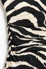 Vestido midi entallado de punto elástico con estampado de cebra, escote bote, manga japonesa y detalle fruncido en la cintura.