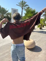 Remera celeste de corte holgado con estampado en rojo en la espalda con el texto "ittaistars", "European Tour by Ittai Stars Company" y el logo de la marca.