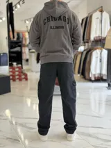 Canguro oversize beige con capucha y cordones ajustables, bolsillo tipo canguro y pequeño bordado en el pecho.