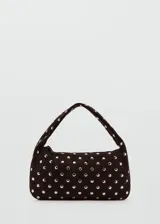 Bolso de hombro tipo baguette confeccionado en piel bovina color marrón oscuro, con diseño estructurado y superficie decorada con tachas metálicas plateadas distribuidas uniformemente. Cuenta con cierre superior y asa integrada.