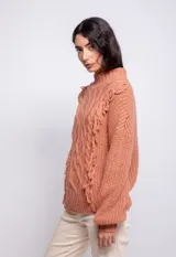 Sweater color crema de tejido trenzado con cuello alto, mangas largas abullonadas y detalle de flecos en el frente.