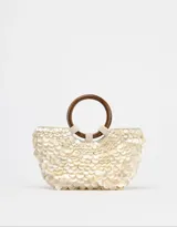 Bolso de mano con forma de media luna cubierto de perlas sintéticas. Tiene asas circulares de madera y detalles de cuentas en la unión con el cuerpo del bolso.