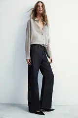 Camisa fluida de corte oversize confeccionada en mezcla de viscosa, con diseño de rayas verticales finas en tono beige sobre fondo blanco. Presenta cuello solapa, cierre frontal con botones, manga larga con puños y un bolsillo de plastrón en el pecho.