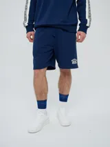 Bermuda de felpa azul marino con cordón ajustable en la cintura, bolsillos laterales y el logo de Umbro bordado en blanco en la pierna izquierda.