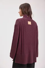 Sweater de punto color bordó con cuello alto y diseño de trenzas en el frente y las mangas. Presenta un corte holgado y largo, con puños y ruedo acanalados.