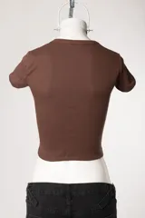 Remera baby tee de morley color chocolate, de calce ajustado al cuerpo y manga corta, con cuello redondo y diseño estampado frontal.