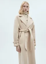 Abrigo largo de lana italiana Manteco en color beige, con diseño envolvente, cuello con solapas y cinturón ajustable a la cintura. Presenta mangas largas con trabillas en los puños y bolsillos laterales.