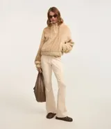 Pantalón de sastrería modelo flare en color beige, confeccionado en tejido de viscosa. Presenta un diseño de tiro alto con lazo ajustable en la cintura y detalle de friso vertical a lo largo de las piernas que estiliza la figura.