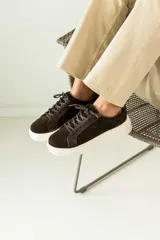 Zapatillas urbanas de cuero, color marrón oscuro, con paneles de gamuza y cuero liso, cordones al tono y suela de plataforma blanca.