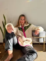 Canguro de polar color crema con bloques de color verde militar en la parte superior y fucsia en los bordes y cierre.