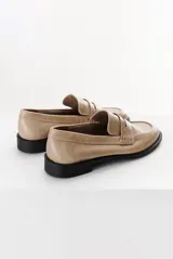 Mocasín color marrón claro, con capellada de cuero liso y aplique de gamuza en marrón oscuro. Tiene punta redondeada y suela plana de goma negra.