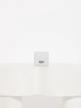 Mini billetera gris de cuero vacuno graneado con matelasseado en forma de V y aplique metálico con forma de labios. Interior con divisiones para tarjetas y forrería de tejido jacquard.