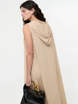 Vestido largo color beige, tipo túnica hoodie, de silueta amplia, con escote en V y capucha. Sin mangas.
