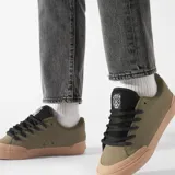 Championes de skate color verde oliva con suela marrón, cordones negros y detalles en negro en el cuello.