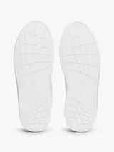 Zapatillas de tenis de corte bajo de la marca Tommy Hilfiger, confeccionadas en piel napa de color blanco. Presentan cordones, punta redonda, suela de goma y detalles distintivos como un pequeño logo esmaltado en el lateral y el nombre de la marca en la lengüeta.