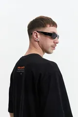 Remera negra de manga corta con corte oversize y cuello redondo. Presenta un estampado pequeño en la espalda con texto en naranja y blanco que dice "Free Spirits Freedom & Waves All Day / Every Day".