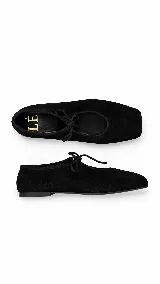 Balerina de gamuza color negro con punta cuadrada y cordones decorativos en la parte superior.