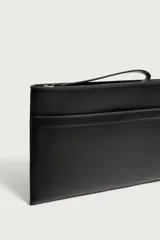 Bolso tipo sobre negro de textura granulada con detalles lisos, cierre superior con cremallera y asa de mano corta.