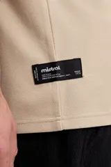 Remera de manga corta color beige con tejido texturado y pequeño logo impreso en el pecho.