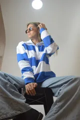 Sweater de punto a rayas horizontales azules y blancas, con cuello polo y cierre parcial con cremallera.