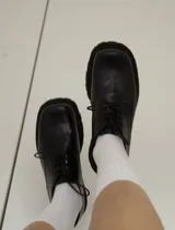 Zapato acordonado de cuero negro con punta cuadrada y suela track.