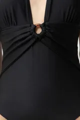 Malla enteriza negra con escote halter y aro carey en el centro del busto.