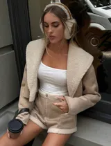 Conjunto de chaqueta corta color beige con cuello de piel sintética y short a juego.