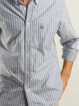 Camisa de corte regular confeccionada en tejido Oxford de algodón, con diseño de rayas verticales finas. Presenta cuello abotonado, cierre frontal con botones y un bolsillo en el pecho.