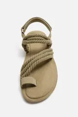 Sandalia color arena con tiras de tejido trenzado y ajuste con velcro en el tobillo.