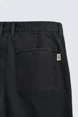 Pantalón de corte carrot fit confeccionado en tejido de algodón con estructura diagonal y efecto lavado. Presenta bolsillos frontales con bolsillo cerillero, bolsillos traseros de plastrón y cierre frontal con cremallera y botón.
