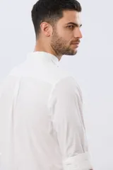 Camisa de lino y algodón color blanco, con cuello mao, manga larga y cierre frontal de botones. Presenta un pequeño logo bordado en el pecho.