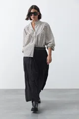 Falda larga de silueta amplia y caída fluida, con cintura elástica y textura arrugada.
