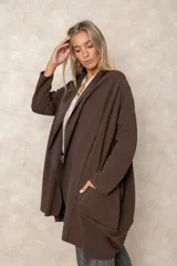 Saco tipo cárdigan largo de color chocolate, con frente abierto, mangas largas y bolsillos laterales amplios. Presenta una caída fluida y un diseño minimalista y elegante.