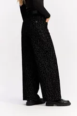 Jean de corte wide leg y tiro medio, confeccionado en algodón con estampado animal print en tonos negros. Presenta un diseño de pierna amplia y cierre frontal con botón y cremallera.