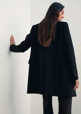 Abrigo midi de doble botonadura en color negro, confeccionado en mezcla de lana. Presenta cuello con solapas de muesca, manga larga y dos bolsillos laterales con solapa.
