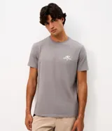 Remera gris de manga corta con cuello redondo, confeccionada en algodón peruano. Presenta un pequeño estampado en el pecho con diseño de ola y la inscripción 'Good Times Sun & Chill Club'.