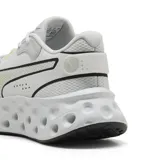 Championes Puma modelo Softride Frequence, color gris claro con detalles en amarillo flúor. Presentan una suela con diseño perforado distintivo y el logo de la marca en el lateral.