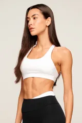 Top deportivo blanco de poliamida con diseño de espalda nadador, breteles medios y banda elástica inferior para mayor soporte. Cuenta con forro interno y entrada para copas removibles.